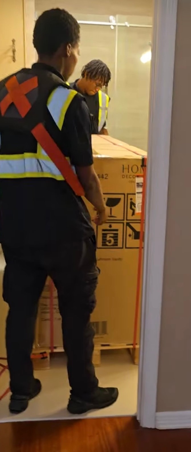 TTC crew lifting and guiding a large boxed item through a doorway